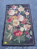 Full view of the vintage hooked rug showing overall floral design and condition on dark background.