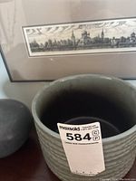 Large gray ceramic round vase with ridged texture and a smaller round vase partially visible.