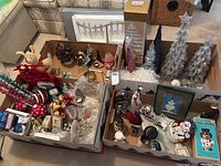Overview of multiple boxes containing assorted Christmas tree decorations, including various ornaments, trees, and figurines.