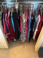 Closet rack with 20 women's short sleeve tops and one sleeveless top, assorted colors and styles.