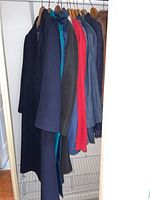 View of 7 coats and jackets hanging on rack showing variety of colors and styles.