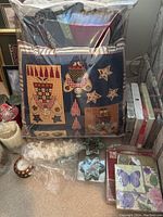 Packaged Christmas-themed patchwork pillows with owls and stars, assorted napkins, white candles and decorative items