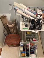 Overall view of TV table with items including cordless phones, posters, trays, doormats, and wooden basket.