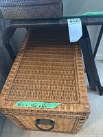 Photo of rattan chest showing woven lid with metal handle and dimensions taped on the front.