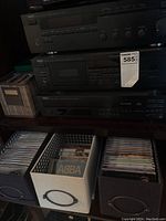 Three stacked Yamaha components on shelf with storage bins of CDs below