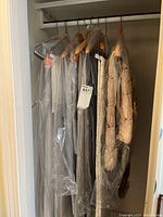 Full view of six table linens hanging on wood hangers in a closet, covered with protective plastic