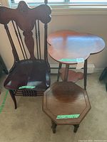 Photo showing vintage carved wooden chair, clover leaf shaped table, and small octagon table grouped together under window light on carpeted floor