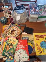 Wide view of lot on table showing children's books, DVDs, records, and decorative doll.