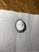Front view of vintage cameo pendant/brooch showing the white carved profile surrounded by small pearls in gold frame.