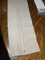 Full view of the thin gold chain laid flat on a surface showing its length and general condition.