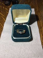 Ring displayed inside a green velvet Jostens jewelry box, showing heart design and diamond detail.
