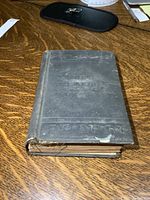 Front and top view of old hardcover book showing overall condition with loose binding and edge wear.
