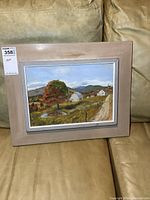 Framed oil painting depicting a rural landscape with a tree and barns, labeled with lot number and price tag