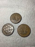 Three old half penny coins dated 1940, 1942, and 1943 showing the sailing ship design and the dates.