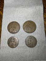 Four old British coins on white cloth: large one pennies 1908 and 1913, half pennies 1917 and 1924, showing Britannia design on reverse side.
