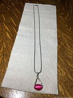 Full length of the necklace with pendant on white cloth to show entire piece.