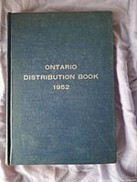Dark green hardcover book with gold text 'Ontario Distribution Book 1952' on the front cover, placed on a soft fabric background.