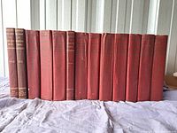 Photo of full set of 14 maroon hardcover books lined side-by-side showing spines with titles and years
