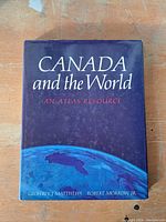 Front cover of the book titled 'CANADA and the World: An Atlas Resource' showing part of the Earth and author names.