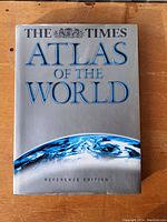 Front cover of The Times Atlas of the World Reference Edition showing a silver cover with blue title text and an image of the Earth.