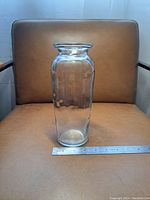 Front view of transparent glass vase showing entire body and flared lip with ruler for size reference.