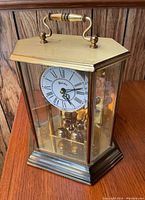 Full view of the Bulova lantern style mantle clock showing brass case, glass sides, and white clock face with Roman numerals.