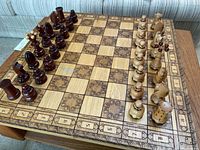 Full view of the chess board with light and dark wooden pieces arranged for play.