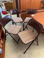 Four Samsonite metal folding chairs, arranged around a table, on carpeted floor, showing upholstery and overall condition.