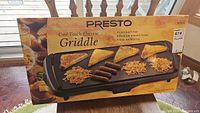 Image of the sealed box featuring the Presto Cool Touch Electric Griddle with food items on the griddle surface and packaging details visible.
