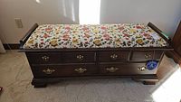 Full exterior photo of the cedar chest showing floral fabric bench top and wood finish with drawer fronts.