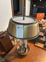 Front and side view of the MCM lamp showing the brushed brass finish, candlestick style bulbs, and perforated shade.