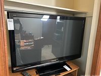 Panasonic Viera 40-inch plasma TV with black bezel and remote control placed nearby on wooden surface.