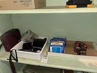 Shelf view showing Pentax Espio 738 camera in original box, multiple boxes of Polaroid 779 film sealed and opened, and six 35mm Blacks film rolls.