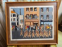 Full view of lithograph in wood frame showing detailed street scene with characters and soldiers.