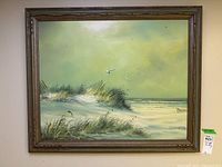 Full view of the oil painting showing the coastal landscape in carved wood frame.
