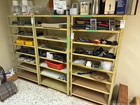 Front view of three yellow metal utility shelves stocked with various items, showing general wear and rust.