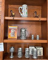 Full view of shelf with ceramic stein, Alte Meister stein in box, shot glasses, and smaller pewter beer cups