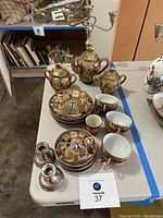 Complete view of the Asian tea set with plates, mugs, teapot, sugar bowl, and candelabra on table.
