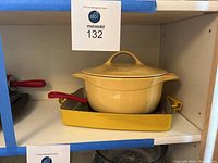 Yellow rectangular baking pan with yellow Calphon covered casserole placed on top shown on shelf.