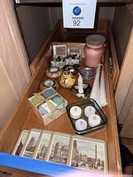Top view of various assorted candles and candle holders in wooden drawer, including tall taper candles, battery tea lights, ceramic candle holders, and small jar.