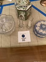Photo showing all lot items including the blue and white ceramic covered candy dish, the Japanese hexagonal urn, two glass candlesticks and the heavy crystal covered candy dish.