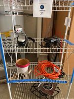 Sony Walkman, orange extension cord, GE caller ID phone, and cream/red decorative pot displayed on wire shelving.