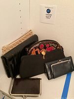 Six assorted handbags and wallets displayed together showing size and material variety.