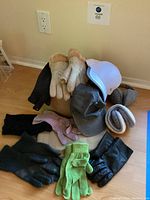 Photo showing hats, gloves, mittens, and earmuffs arranged on wooden floor, illustrating lot contents.