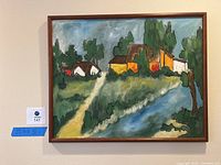 Full view of framed painting showing homes, forest, path and lake, with visible label and size tape which reads 25 inches high by 31 inches wide.