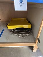 Serving trays inside wooden shelf showing the yellow tray on top of stacked silver trays underneath, also a frosted plastic tray included