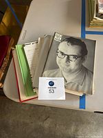 View of papers and a black and white booklet with Steve Allen image on cover laying on a table.