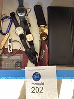 Top-down view of entire lot showing watches, shoe horns, wallet, key chains, and calculator