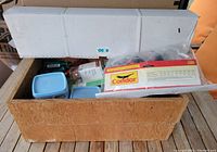 Two wooden boxes filled with assorted hardware and tools including a white box on top and several plastic containers inside.