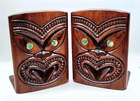 Front view showing the hand carved Polynesian faces on the wooden book ends with abalone shell eyes.